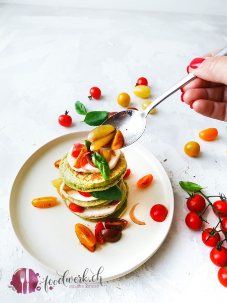Die Pancakes werden mit Tomatensalat und Mozzarella serviert. Im Teig ist noch Basilikum, der die Pancakes herrlich grün färbt.